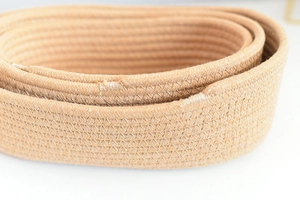 Macro shot of light brown hand-woven cotton rope storage basket with zigzag stitching
