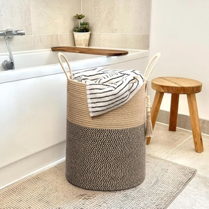 Close-up of dual-tone woven cotton rope laundry basket with reinforced handles and tassel