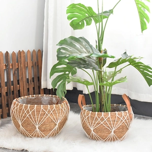 Detail of handwoven plant baskets with white geometric mesh and brown leather handles