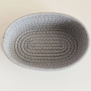 Overhead view showing the tight spiral weaving process of this oval cotton rope basket