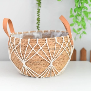 Detail of hand-woven seagrass planter with white macrame net and leather handles
