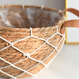 Close-up of woven rattan planter with white rope net detail and leather handle