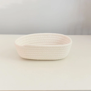 Close-up of oval hand-woven cotton rope storage basket in a creamy off-white finish