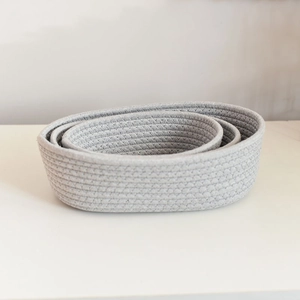 Detailed macro view of nested grey cotton rope woven storage baskets on white surface
