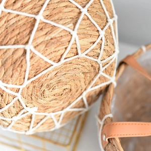 Detail of woven rattan planter with white cotton mesh and leather handle with metal rivets