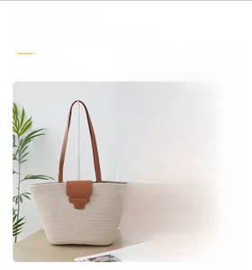 Detail of woven straw beach tote bag with brown leather handles and magnetic closure