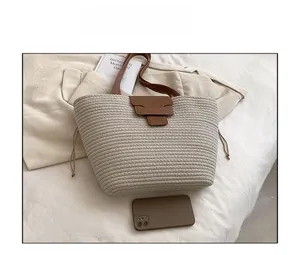 Macro shot of large straw tote bag featuring leather buckle and drawstring detail