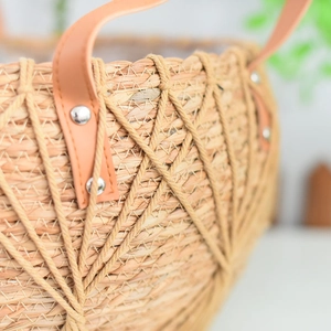 Detail of hand-woven wicker basket with diamond mesh pattern and brown leather handle
