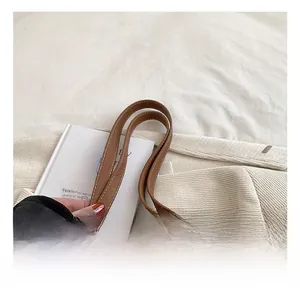 Close-up of brown leather handle with white stitching on woven beach tote bag