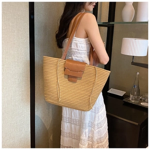 Large straw tote bag with brown leather straps shown on a model for a resort style