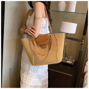 Detailed view of hand-woven straw tote bag with brown leather straps for resort travel