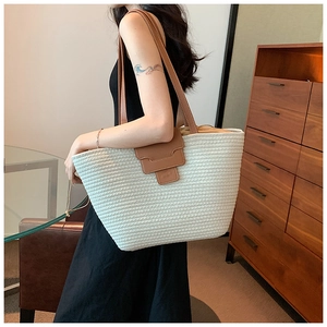 Detail of white woven tote bag with brown leather straps and drawstring lining