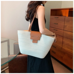 Detailed texture of large straw woven tote bag with brown leather shoulder straps