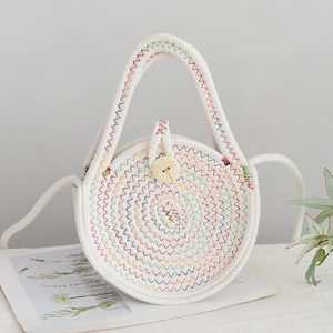 Détail d'un sac cabas en paille blanche avec coutures ondulées et bouton en bois