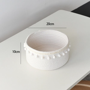 Detail view of round woven cotton rope basket with dimensions 20cm by 10cm and white pom poms