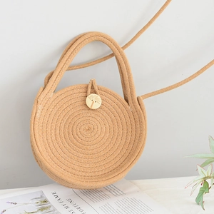 Détail du sac rond en paille avec tissage en spirale, bouton en bois et bandoulière