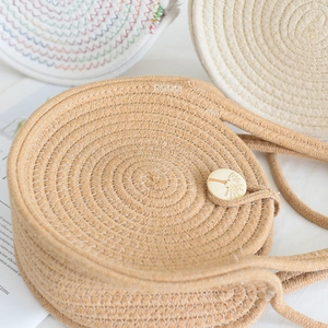 Détail de sacs en paille ronds avec textures tissées et fermoirs en bouton bois