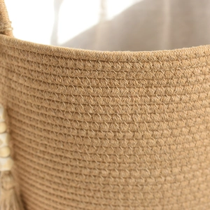 Detailed macro view of woven cotton rope basket with decorative wood beads and tassel