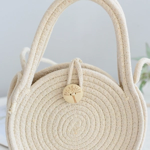 Gros plan du sac en paille tressée crème avec bouton en bois et texture spirale