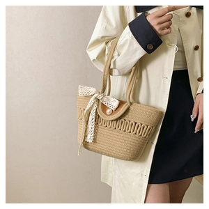 Detail of woven straw tote bag featuring white lace bow and large pearl clasp decoration