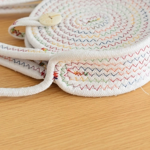 Détail du tissage en coton blanc avec coutures arc-en-ciel en zigzag et bouton en bois