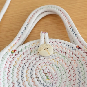 Vue macro du sac en coton tissé avec coutures colorées et bouton en bois gravé