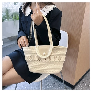 Detail of hand-woven cream tote bag with elegant pearl button and leather flap closure