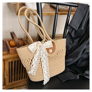 Detail of woven khaki tote bag featuring a white lace bow and a large faux pearl closure