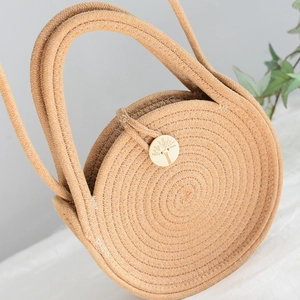 Détail du sac en paille tissé main avec bouton en bois rond et motif de tissage en spirale