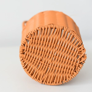 Detail view of cross-woven bottom on bright orange plastic woven flower basket