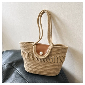 Detail of hand-woven tote bag featuring a leather flap and elegant pearl button closure