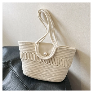 Detailed view of woven cotton shoulder bag featuring leather flap and pearl buckle