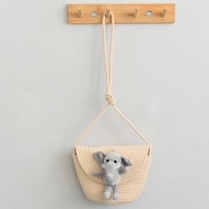 Detail of children's straw crossbody bag featuring a cute plush elephant and cotton rope strap