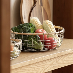 Rustic iron mesh basket with wooden rim filled with fresh vegetables on wooden shelf