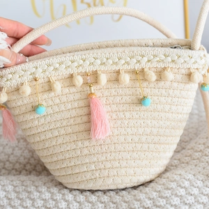 Close-up of hand-woven straw bucket bag with colorful tassels and soft plush pom-poms