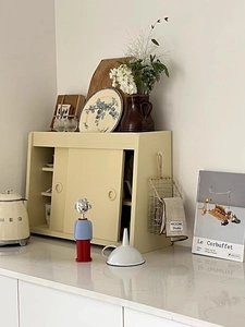 Cream retro metal storage cabinet with double sliding doors on a marble kitchen counter