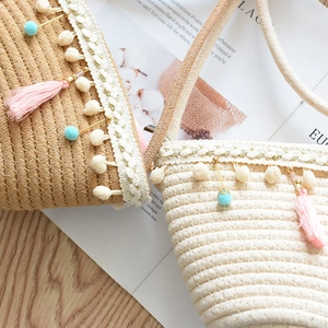 Close-up of woven straw bags with colorful pom-poms, pink tassels and golden beads decor