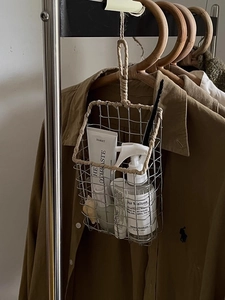 Close-up of metal wire basket with woven rope handle hanging on a wooden hanger