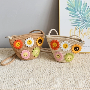 Détail de sacs bandoulière en paille pour enfants avec fleurs au crochet et visages souriants
