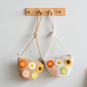 Détail de sacs de téléphone tressés avec broderies de fleurs de soleil souriantes colorées