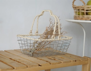 Detail of silver wire storage basket with handcrafted woven handles on a wooden bench