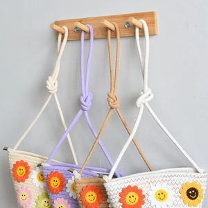 Détail de sacs à bandoulière tissés en quatre couleurs avec fleurs souriantes crochet