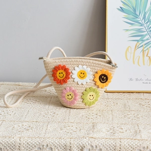 Détail du sac à bandoulière en paille tressée avec fleurs colorées au crochet et sourire