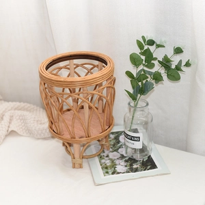 Close-up of hand-woven rattan planter basket with three solid wood legs in a Nordic style