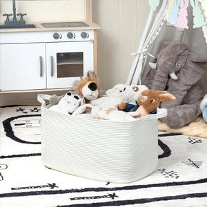 Large white woven cotton rope storage basket with handles filled with plush toys