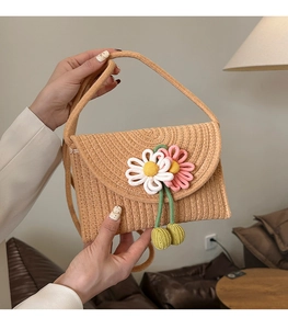Close-up of handmade woven straw crossbody bag featuring pink and white crochet flowers