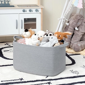 Close-up of gray woven cotton rope storage basket filled with plush toys in a playroom