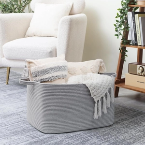 Detail of grey cotton rope storage basket containing cushions and a waffle blanket