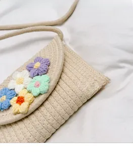 Detail of hand-woven straw crossbody bag with colorful crochet flower decorations