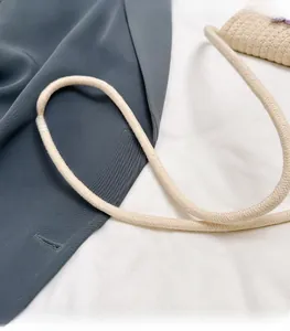 Close-up of beige woven crossbody bag showing the thick cotton rope shoulder strap texture